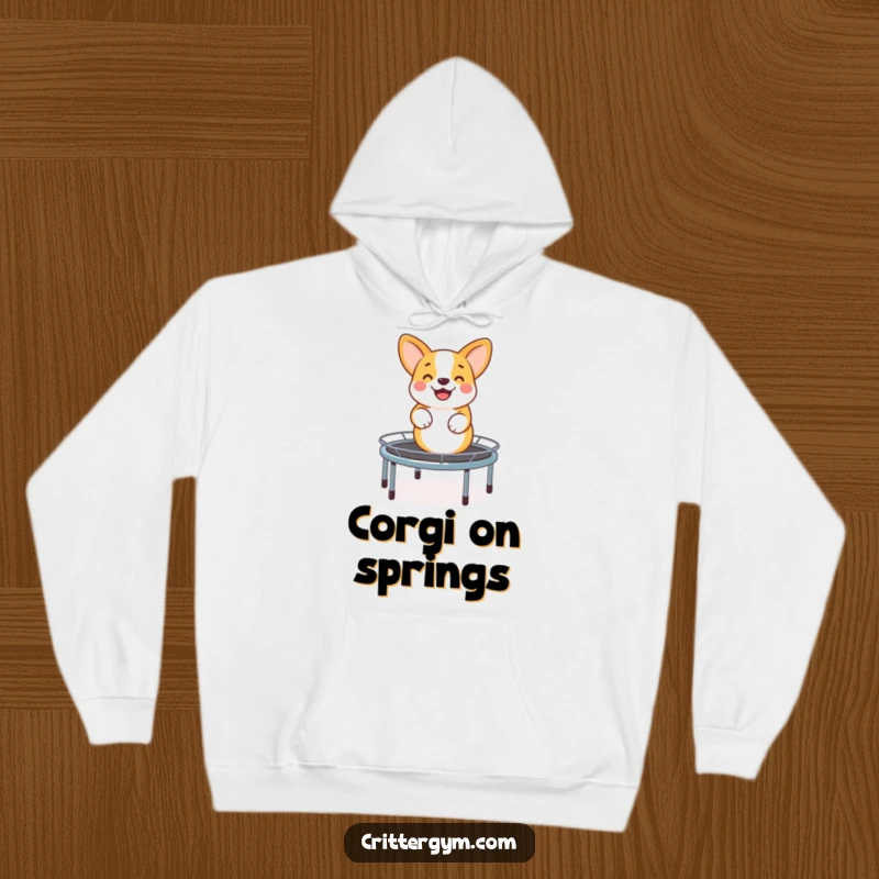 Funny hoodie with a happy corgi energetically bouncing on a miniature trampoline, designed for comfort and a splash of playful, humorous joy.